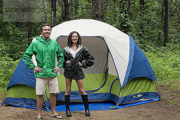 Porträt von Freunden mit Händen auf den Hüften vor dem Zelt im Wald stehend