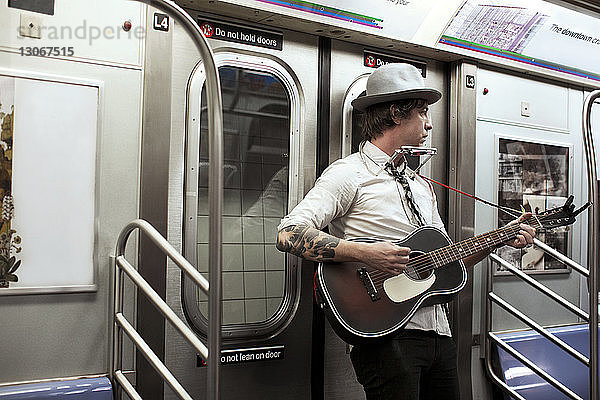 Straßenmusikant spielt Gitarre in U-Bahn-Zug