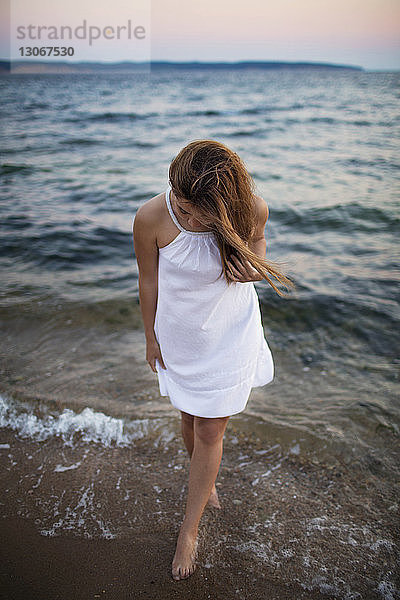 Frau schaut nach unten  während sie am Strand am Ufer steht