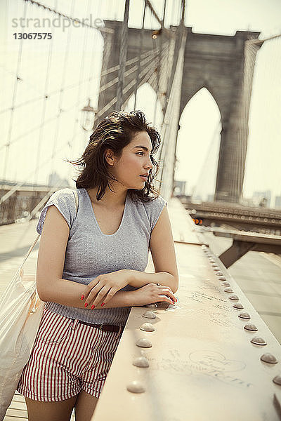 Nachdenkliche Frau steht an der Brooklyn Bridge in der Stadt