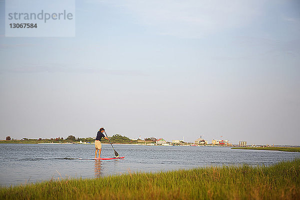 Rückansicht eines Mannes beim Paddelbootfahren im See gegen den Himmel