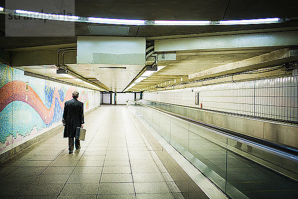 Rückansicht eines in der U-Bahn gehenden Geschäftsmannes mit Aktentasche