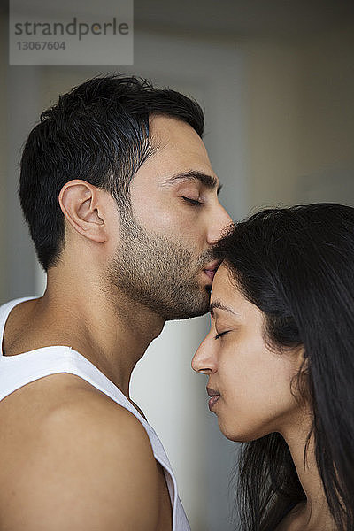 Seitenansicht eines Mannes  der eine Frau auf die Stirn küsst