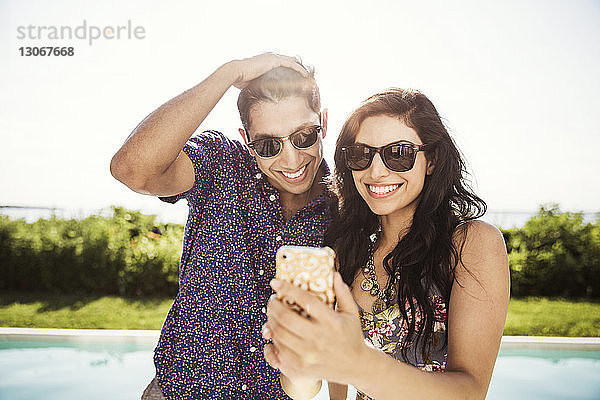 Glückliches Paar  das Selfie nimmt  während es gegen den klaren Himmel steht