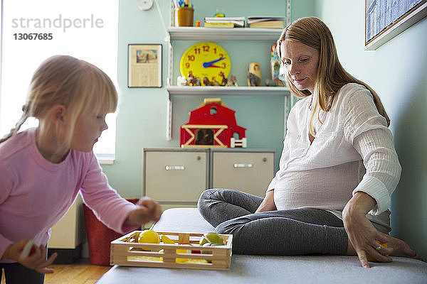 Frau sieht Mädchen an  das zu Hause mit Spielzeug spielt