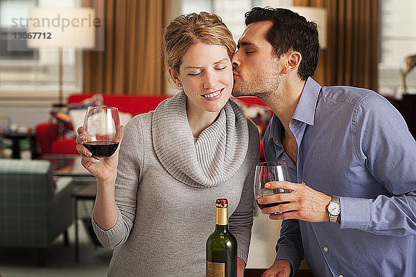 Mann küsst Freundin mit Weinglas