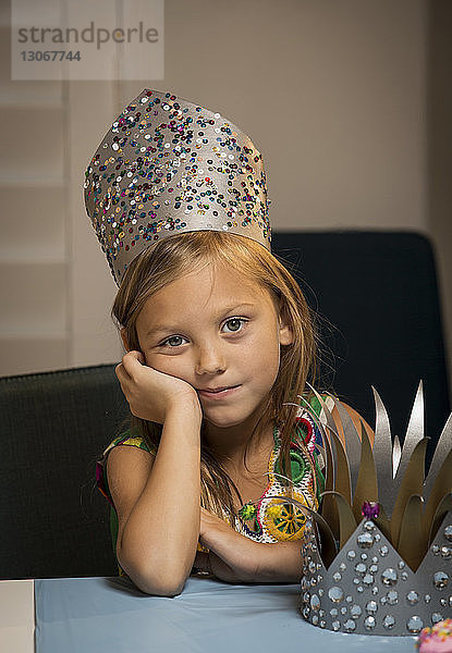 Porträt eines Mädchens mit Krone bei Tisch zu Hause sitzend