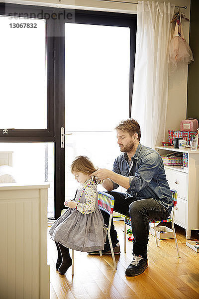 Vater bindet der Tochter zu Hause die Haare