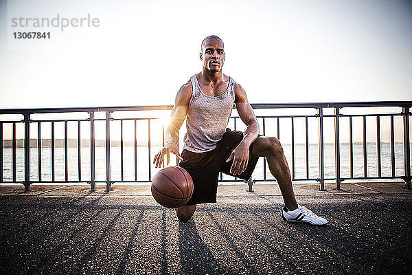 Porträt eines Sportlers  der mit Basketball auf der Brücke gegen den klaren Himmel spielt