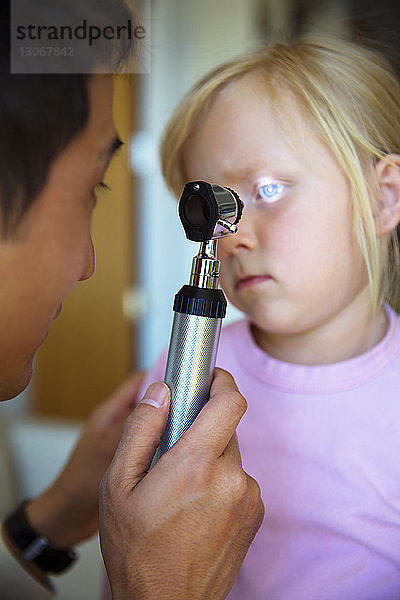 Arzt untersucht das Auge des Mädchens