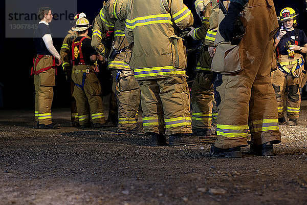 Feuerwehrleute stehen nachts auf dem Feld