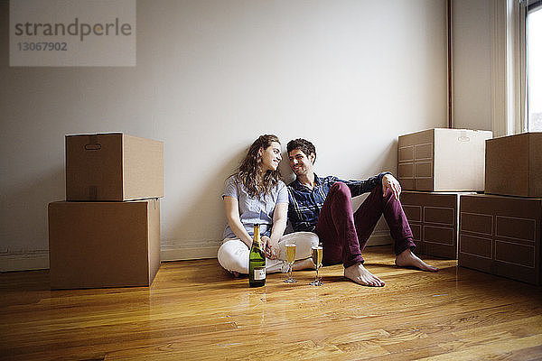 Paar mit Weingläsern sitzt zu Hause auf dem Boden
