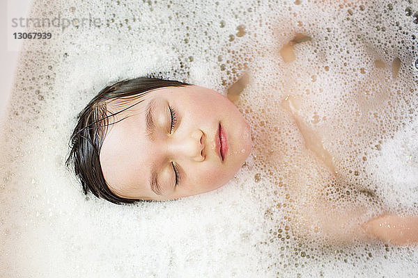 Draufsicht eines Jungen mit geschlossenen Augen in der Badewanne
