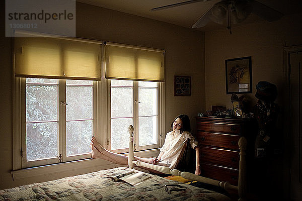Frau sitzt zu Hause am Fenster