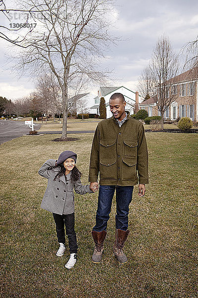 Porträt eines glücklichen Mädchens  das mit seinem Vater im Hinterhof gegen den Himmel steht