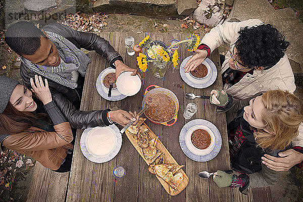 Hochwinkelansicht von Freunden  die im Freien an einem Holztisch essen