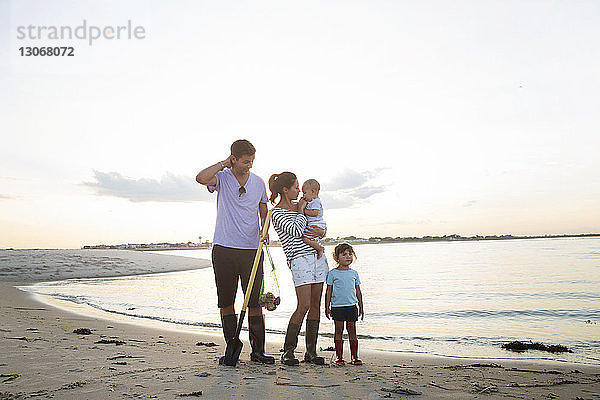Familie in voller Länge am Strand gegen den Himmel stehend