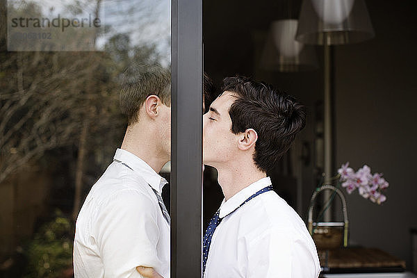 Seitenansicht eines schwulen Paares  das sich küsst  während es an der Tür steht