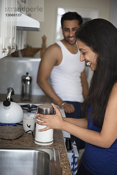 Mann sieht Frau beim Kaffeekochen an  während er in der Küche steht