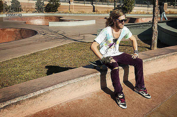 Mann mit Skateboard entspannt sich im Park