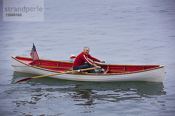 Glücklicher älterer Mann im Ruderboot auf dem See