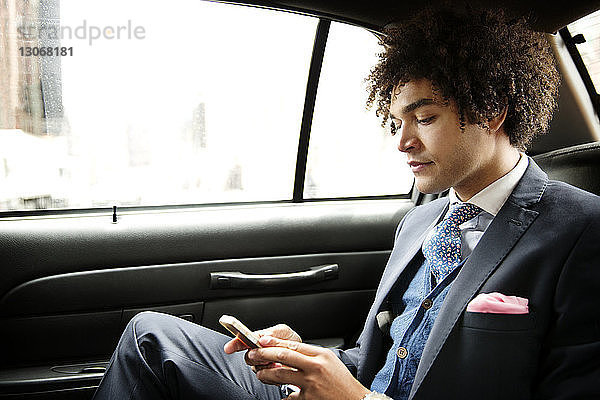 Geschäftsmann benutzt Mobiltelefon  während er im Auto sitzt
