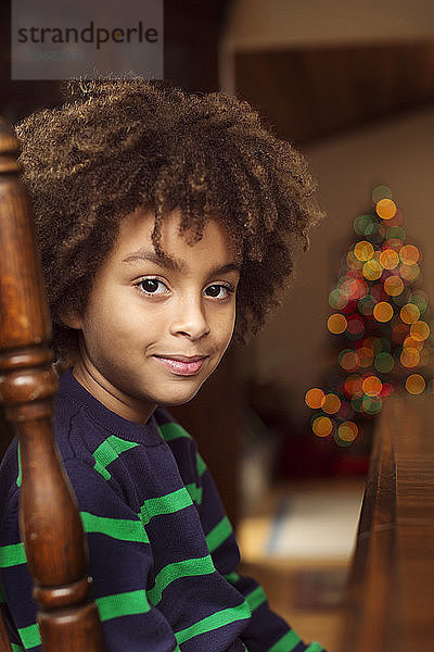 Porträt eines lächelnden Jungen  der zu Hause auf einem Stuhl sitzt