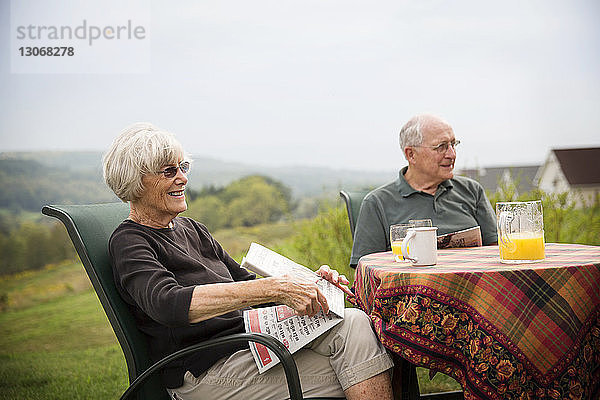 Älteres Ehepaar sitzt am Tisch auf Feld gegen Himmel
