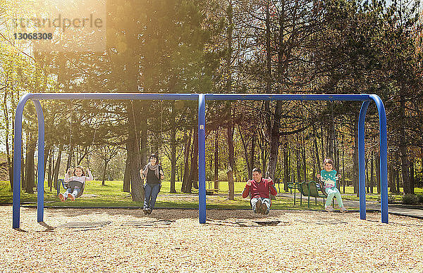 Porträt einer glücklichen Familie beim Schaukeln auf dem Spielplatz