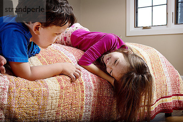 Kinder  die sich zu Hause im Bett liegend anschauen