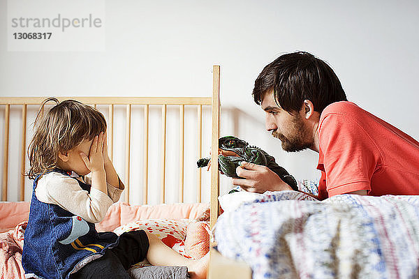 Vater und Tochter spielen zu Hause mit Spielzeug im Bett