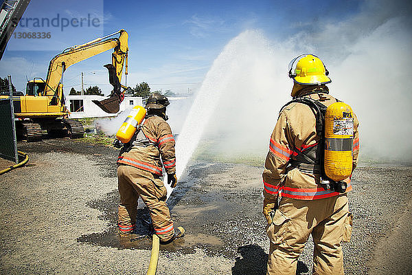 Feuerwehrleute  die an sonnigen Tagen Wasser versprühen  um Brände zu stoppen