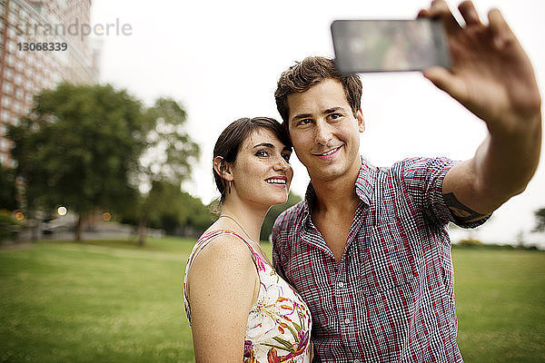 Freunde nehmen Selfie  während sie im Park gegen den Himmel stehen