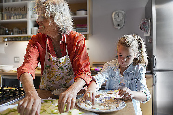 Frau mit Enkelin bereitet Essen in der Küche zu