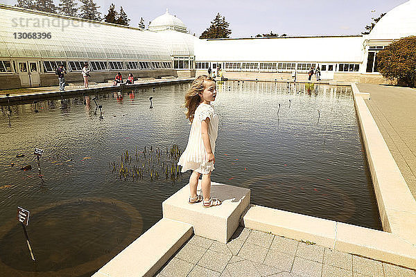 Mädchen steht am Teich an einem sonnigen Tag