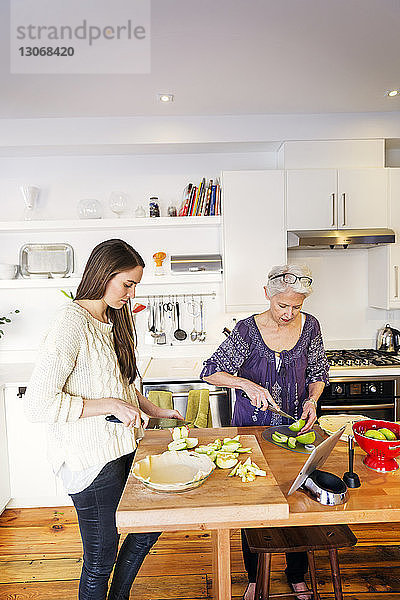 Mutter und Tochter backen Apfelkuchen in der Küche