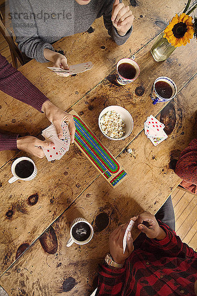 Schrägansicht auf Freunde  die beim Kaffeetrinken zu Hause Karten spielen