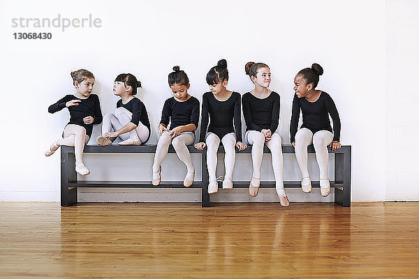 Niedliche Ballerinas sitzen im Studio auf der Bank