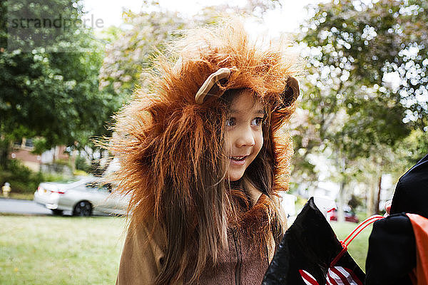 Fröhliches Mädchen in Halloween-Kostüm  das während eines Streichs oder einer Behandlung auf dem Weg steht