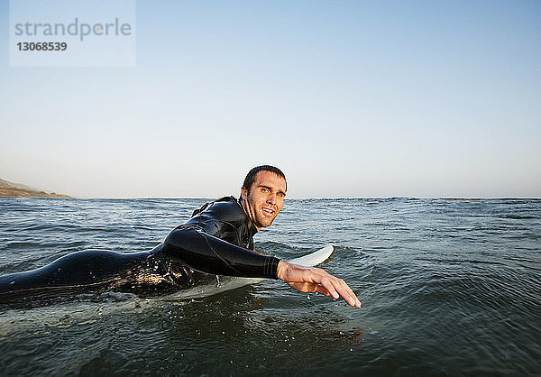Porträt eines Mannes beim Surfen im Meer vor klarem Himmel
