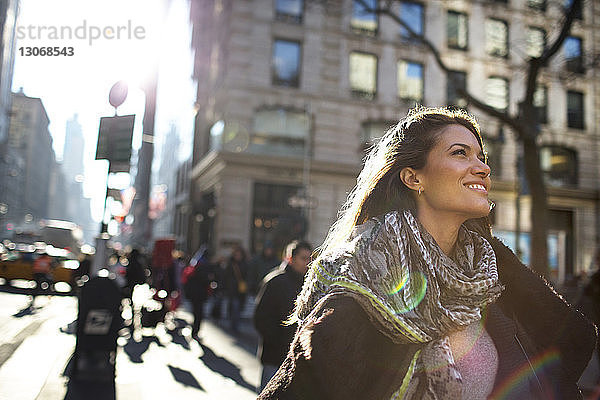 Lächelnde Frau schaut auf  während sie auf einem Fußweg in der Stadt geht