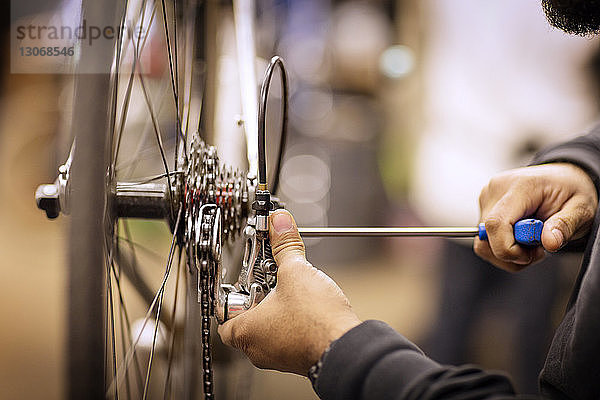 Ausschnitt eines Mannes  der ein Fahrrad in einer Werkstatt repariert