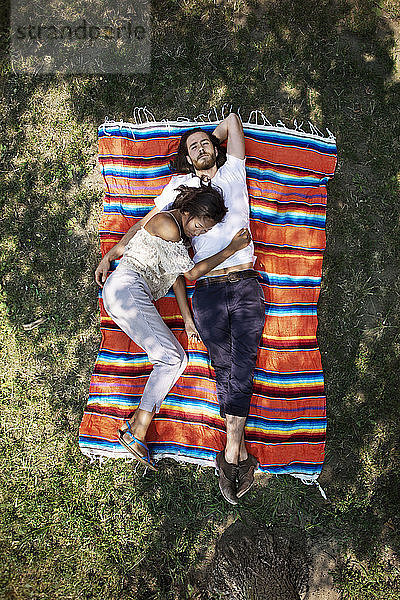 Draufsicht auf ein Paar  das im Park auf einer Decke liegt