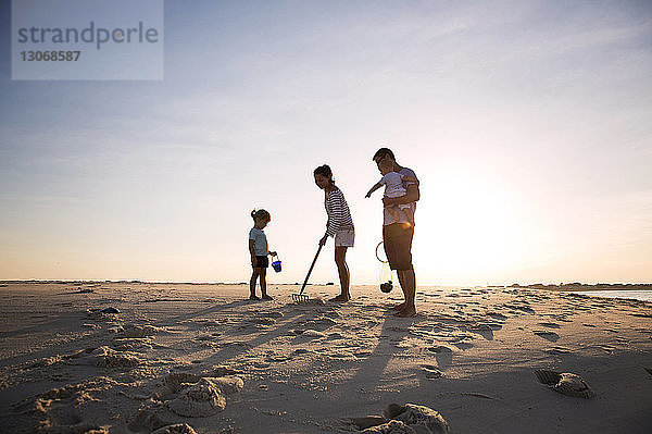 Familie sucht Muscheln am Strand gegen den Himmel