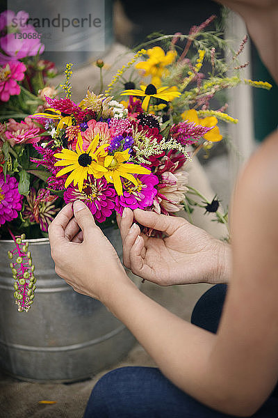 Ausgeschnittenes Bild einer Frau  die Blumen in einem Topf zum Verkauf im Geschäft berührt