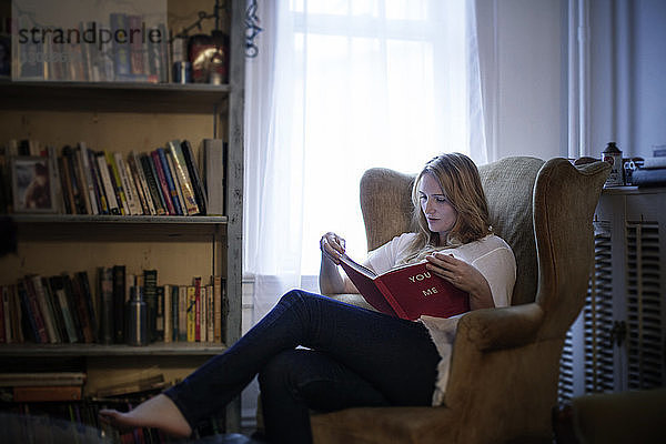 Frau liest Buch zu Hause