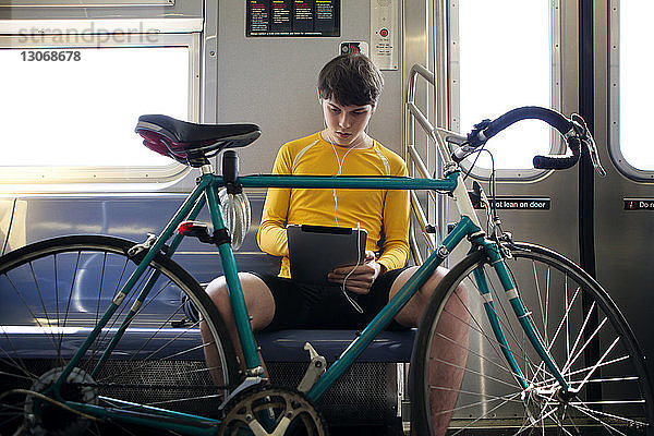 Seitenansicht eines Mannes mit Fahrrad  der am Bahnsteig auf den Zug wartet