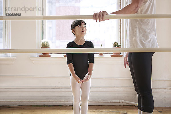 Niedliche Ballerina schaut auf männlichen Lehrer im Ballettstudio