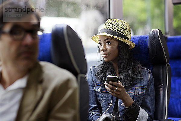 Frau schaut weg  während sie ein Mobiltelefon im Bus benutzt