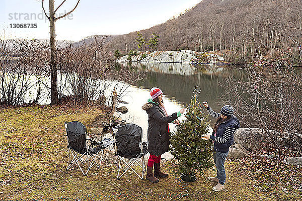 Freunde schmücken Weihnachtsbaum auf Campingplatz im Wald